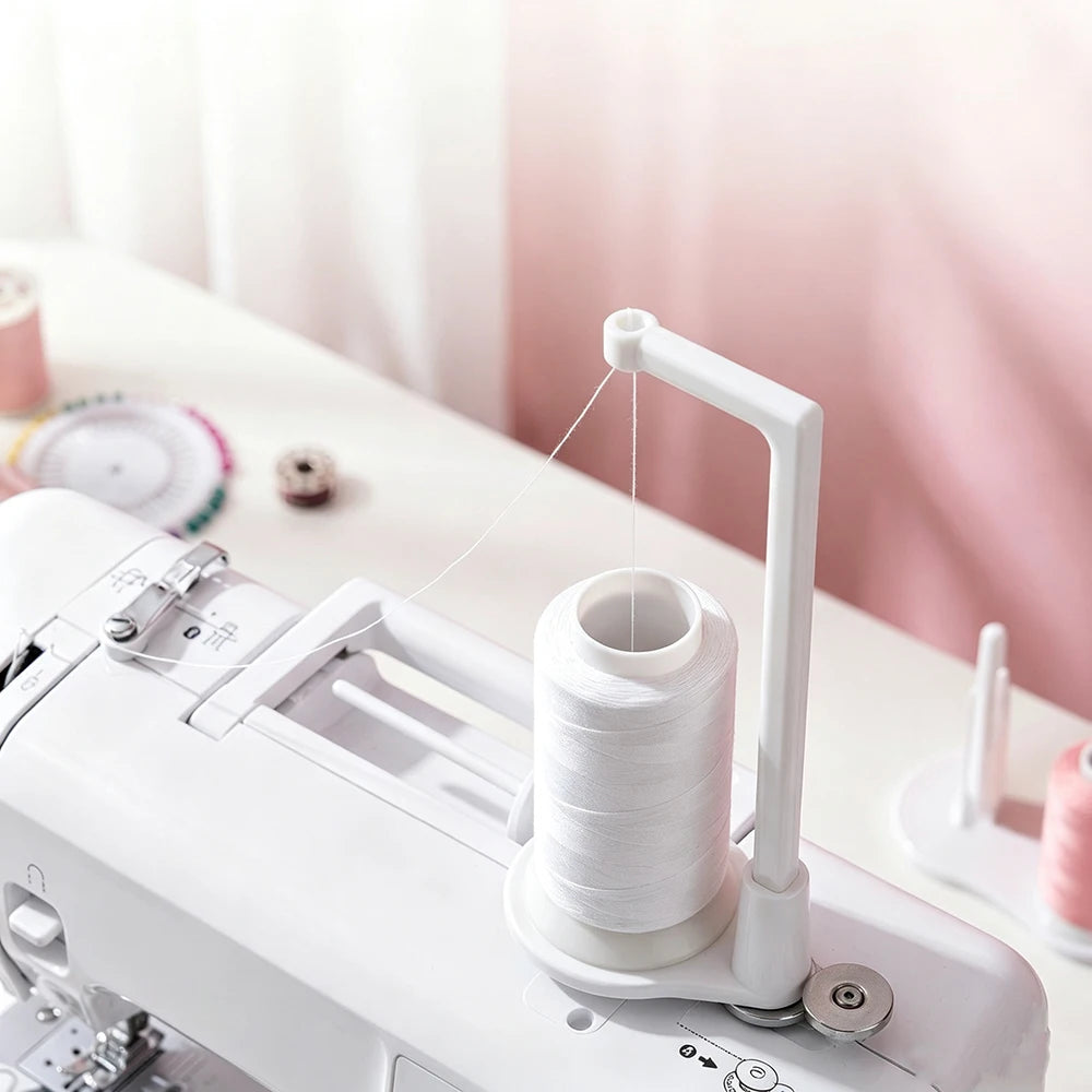 A white vertical sewing machine spool holder with a thread guide is shown on a white surface.
