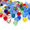 A pile of faceted bicone crystal glass beads in various colors including blue, green, red, and yellow.