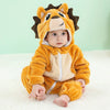 A baby wearing an adorable orange and tan animal hooded romper with ears, sitting on a white surface.
