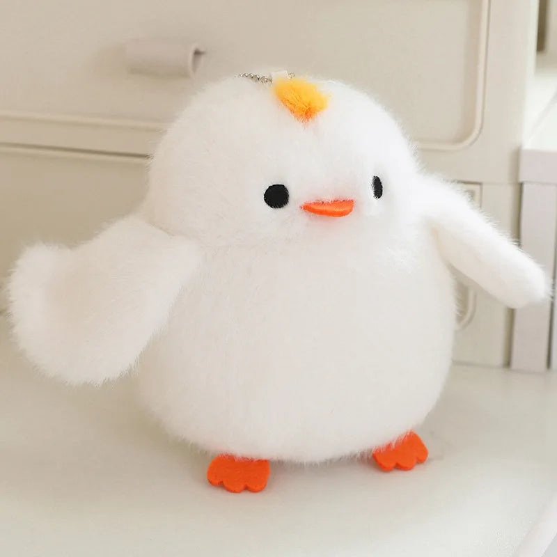 A white cartoon bird plush with orange accents sits on a white surface.