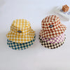 A stack of three checkerboard bucket hats in yellow, brown, and blue on a white surface.