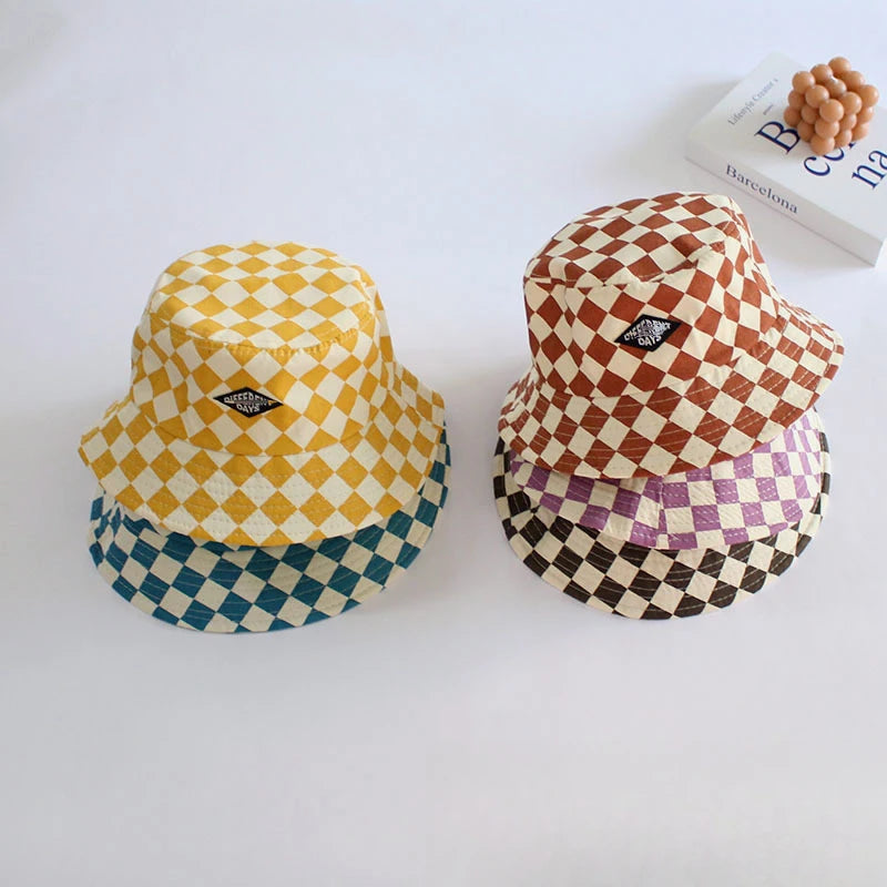 A stack of three checkerboard bucket hats in yellow, brown, and blue on a white surface.