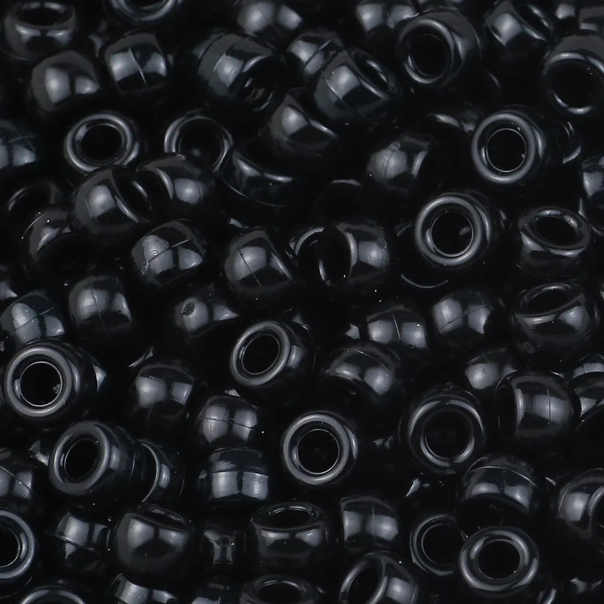 A close-up view of small, black pony beads for jewelry making and crafts.
