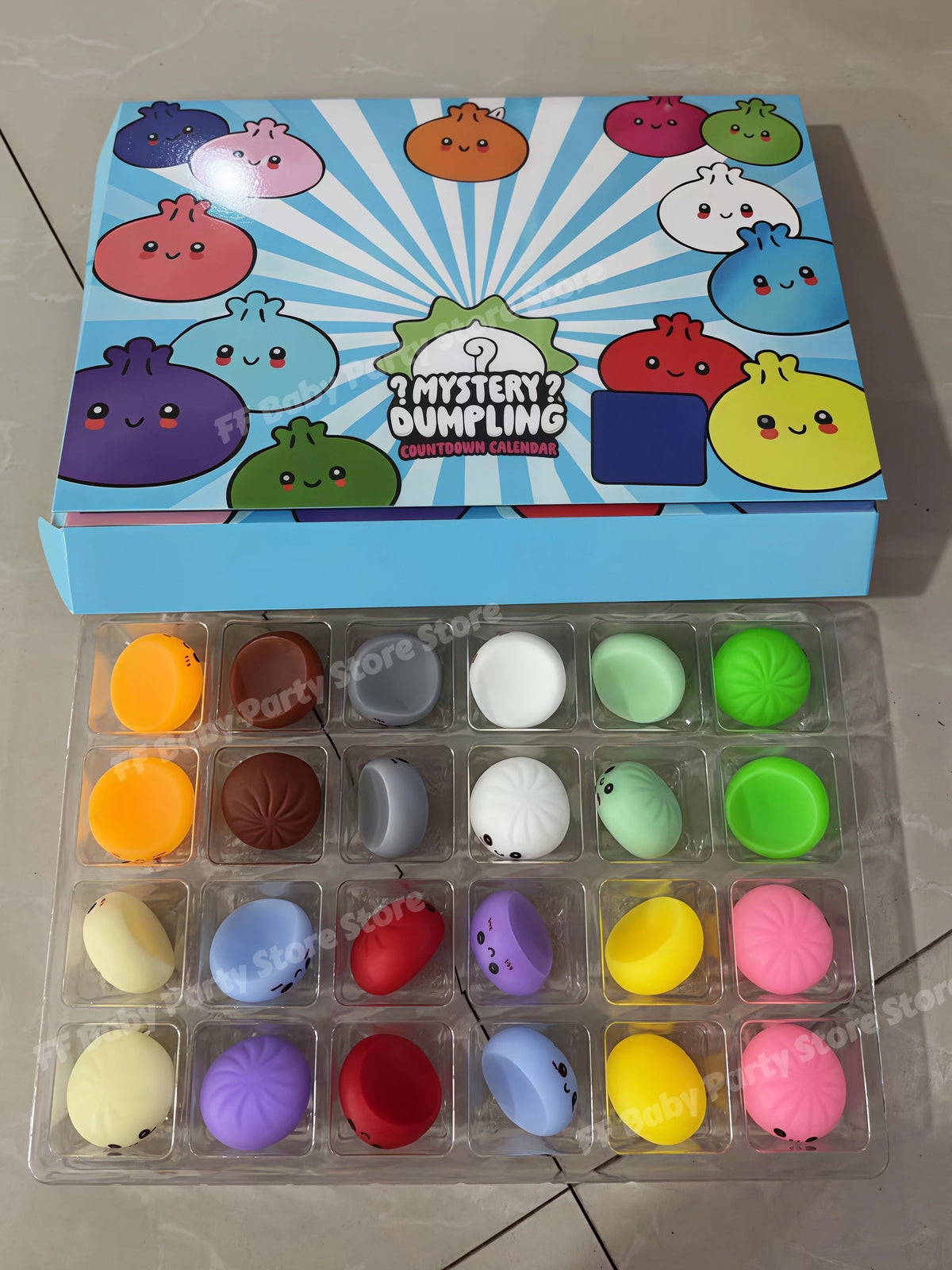 A box of maltose-filled squishy toys with a sunburst design and a tray of various colorful squishy toys.