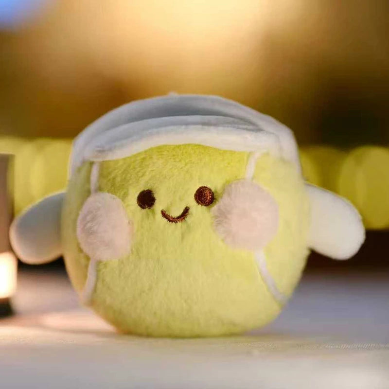 A soft yellow plush ball with white accents, resembling a sports ball charm.
