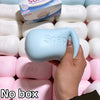 A hand holds a light blue soap ball squishy fidget toy against a background of pink and white squishies.