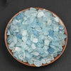 A pile of light blue to cyan aquamarine chips in a terracotta bowl.