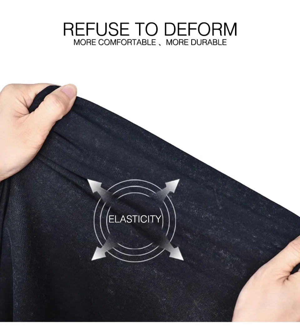 A hand is pulling a black t-shirt to demonstrate its elasticity and durability.