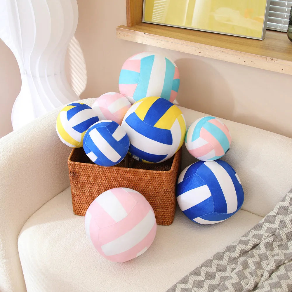 A collection of colorful, striped soft plush volleyball pillows in various shades of blue, pink, and white resting on a light