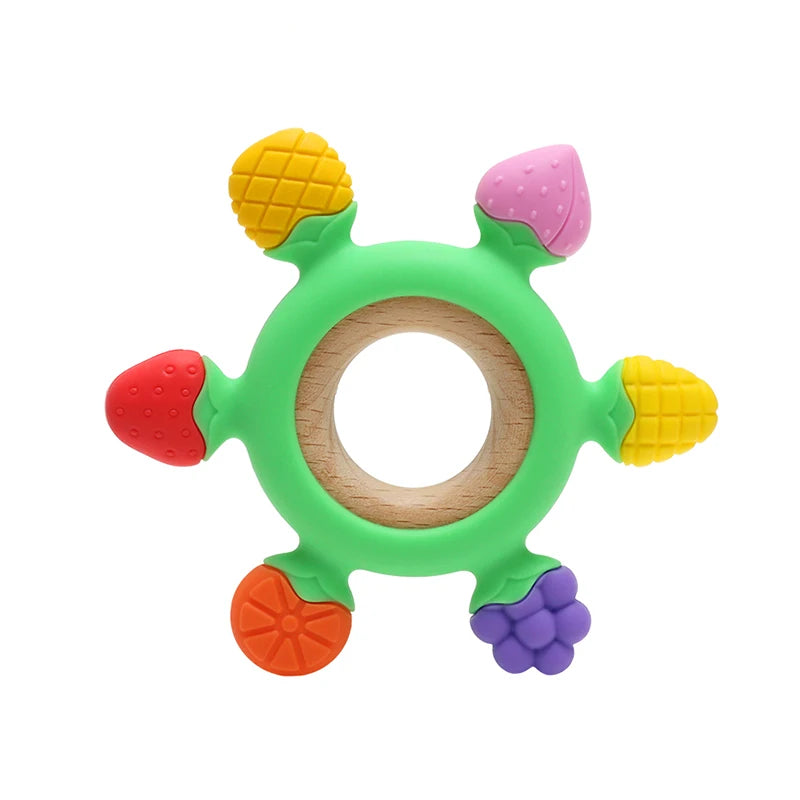 A green silicone teether shaped like a rudder with colorful silicone protrusions and a wooden ring.