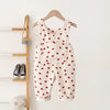 Toddler corduroy overalls in cream fabric with red heart embroidery hanging on a wooden rack.