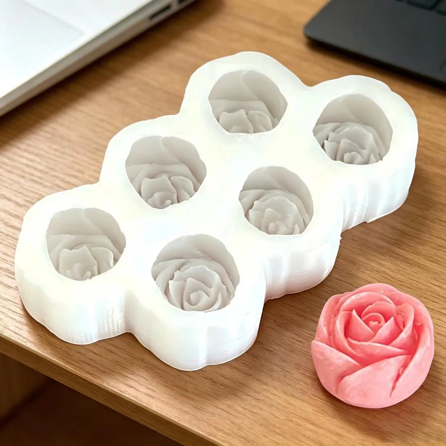 A white silicone mold set with multiple rose flower shapes is displayed on a wooden surface.