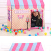 A pink and blue striped play tent decorated like a waffle lane with colorful balls on the floor.