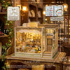 A detailed wooden miniature dollhouse kit featuring a glass display case and interior furniture.