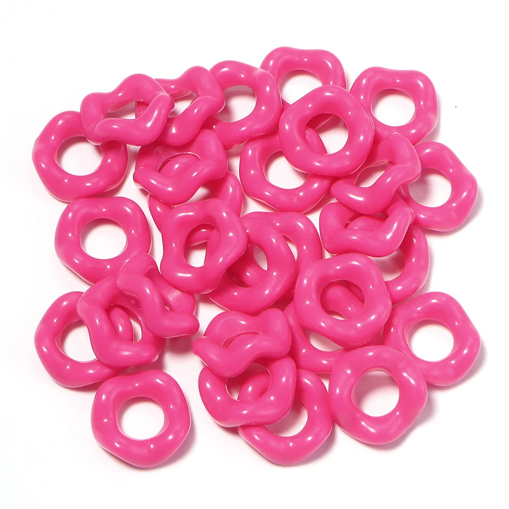 A pile of bright pink acrylic doughnut spacer beads for jewelry making