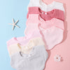 Eine Stapel von drei rosa und weißen Baumwoll-Baby-Kragen oder Oberteilen für Säuglinge auf einem hellblauen Hintergrund.
