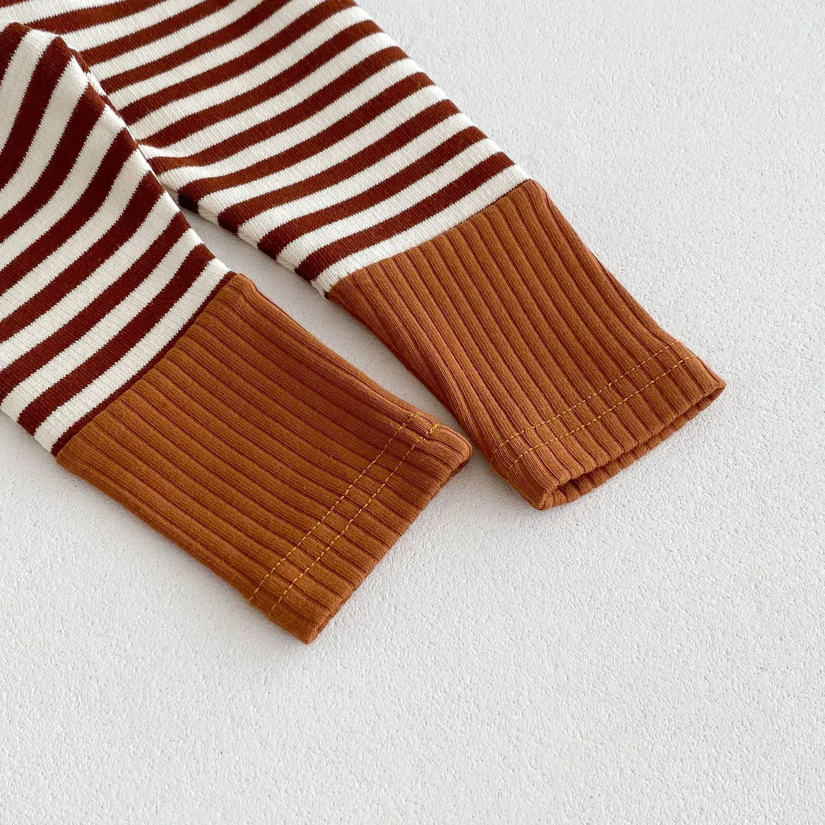 A close-up of a brown and white striped baby legging with a ribbed cuff.