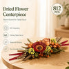 Dried flower centerpiece featuring various autumnal colors and textures arranged on a wooden table.