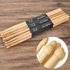 A set of classic maple drumsticks with black labels laid out on a wooden surface.