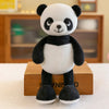 A cute panda plush toy with black and white fur sitting on a wooden box.