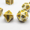 A close-up of several yellow and white polyhedral dice, including a d6, d8, and d10, scattered on a white surface.