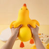 Hands are squeezing a large yellow squishy duck stress ball fidget toy against a light yellow background.