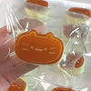 A hand holds an orange cat shaped squishy stress-relief toy in clear packaging.