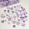 A collection of mixed purple and clear acrylic bow and flower beads for jewelry making.
