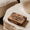 A wooden miniature Ouija board with a drawer resting on a white stone surface.