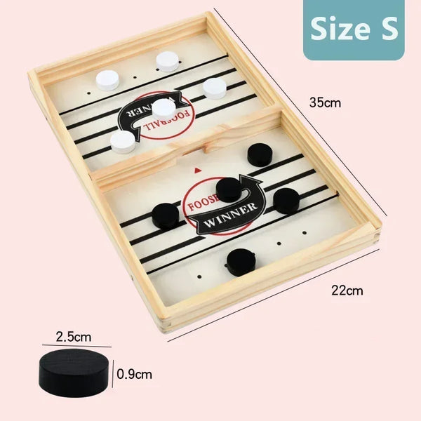 A wooden foosball table game with black and white balls and a winner marker, shown from above.