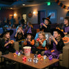 Three young girls holding Halloween pumpkin and ghost squishy stress balls in a dimly lit room.