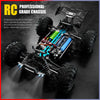 A professional-grade RC monster truck chassis with large tires and blue components, illuminated by bright LED headlights.