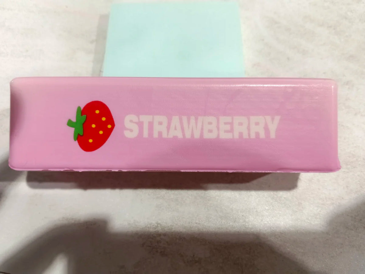 A pink squishy butter stick fidget toy with a strawberry design and the word STRAWBERRY printed on it.