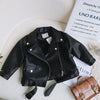 Black kids faux leather zip-up jacket lying on a white textured surface.