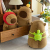 A collection of adorable capybara plush toys, including one with a strawberry, displayed on a wooden shelf.