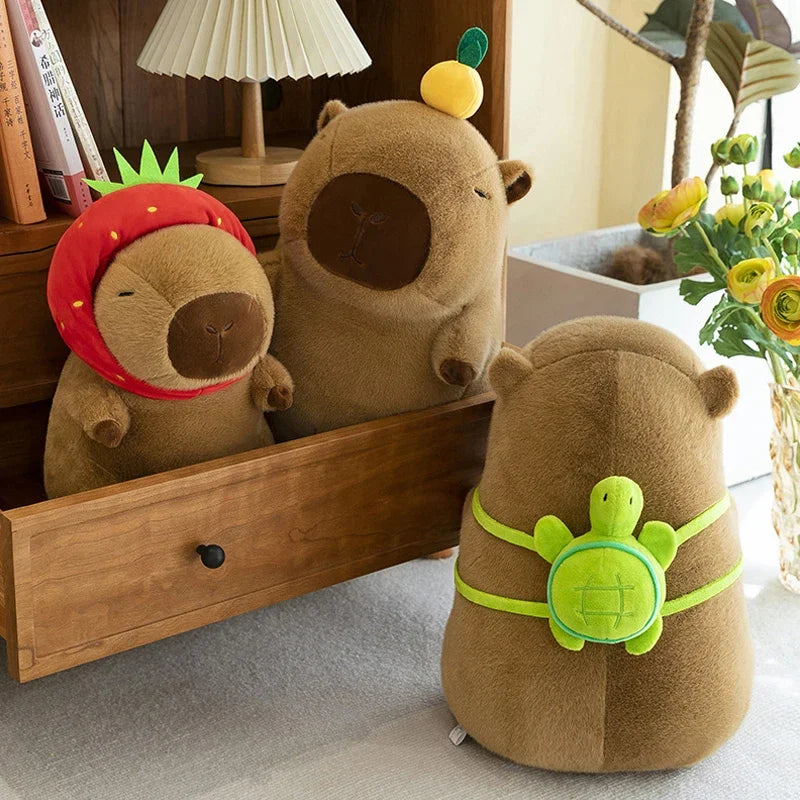 A collection of adorable capybara plush toys, including one with a strawberry, displayed on a wooden shelf.