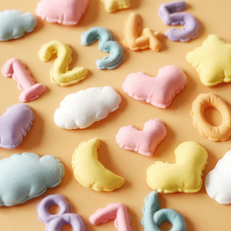 A collection of pastel silicone molds shaped like clouds, hearts, and letters in various colors for baking and crafts.