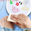 A hand wipes a colorful floating doodle art kit on a white plate with green and pink floral designs.