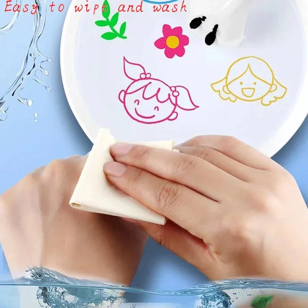 Una mano limpia un kit de arte doodle flotante y colorido sobre un plato blanco con diseños florales verdes y rosas.