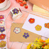 A collection of colorful glitter flower round stickers on a white background, next to a brown envelope and a box.