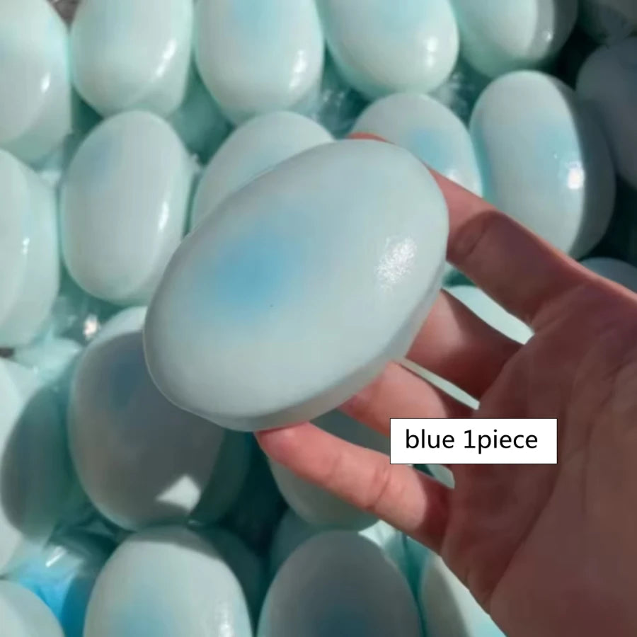 A hand holds a light blue squishy cheese cake stress relief toy surrounded by many similar toys.
