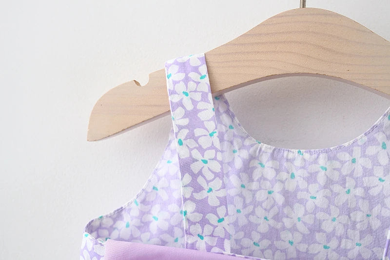 A purple floral baby girl summer dress and sunhat set displayed on a wooden hanger.