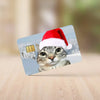 A cat wearing a red Santa hat is featured on a card with a winter background.