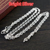Bright silver flattened chain connector for jewelry making displayed on a dark wooden surface.