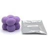 A pile of purple candle dye chips for soy wax, beeswax, and paraffin, next to a sealed plastic bag labeled violet.