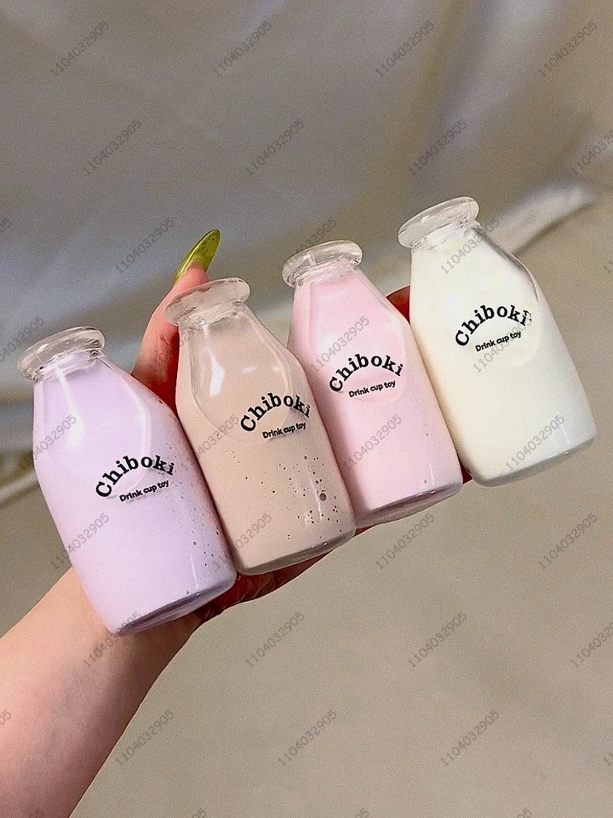 A hand holds three pink and white Chiboki drink cups, a fruit bottle stress ball set.