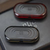 Close-up of a black EDC push slider fidget toy with concentric ridges, showing two different colored versions.
