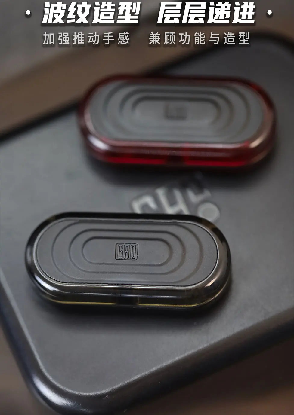 Close-up of a black EDC push slider fidget toy with concentric ridges, showing two different colored versions.