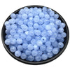 A pile of small, translucent light blue acrylic round beads for jewelry making.