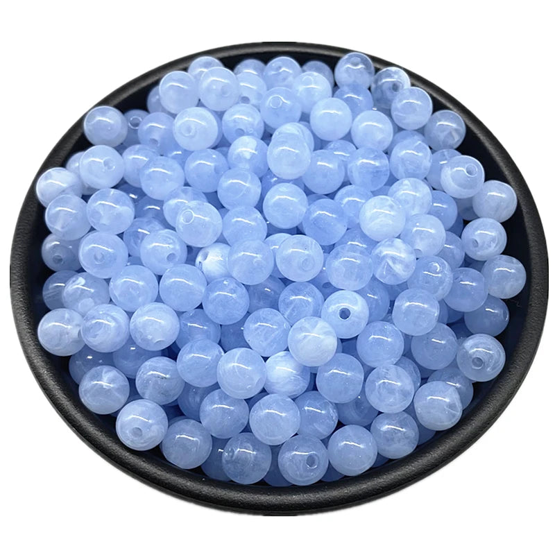 A pile of small, translucent light blue acrylic round beads for jewelry making.